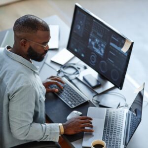 Minimal high angle view at African American software developer working with computers and data systems in office